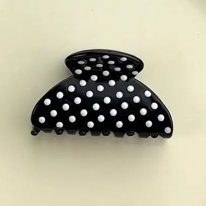 A black claw hair clip with white polka dots
