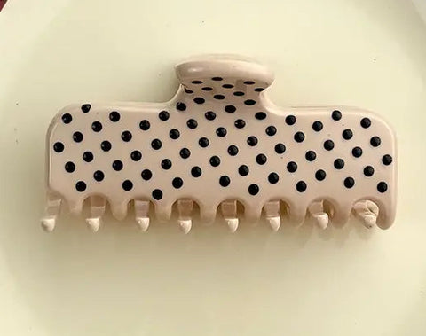 A beige claw hair clip with black polka dots