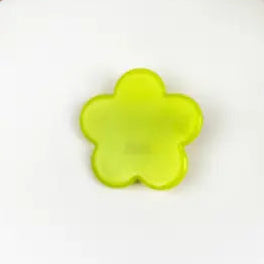 A translucent lime green flower-shaped plastic piece, likely a craft embellishment or small accessory, shown on a plain white surface.