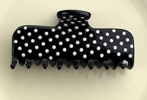 A black claw hair clip with white polka dots